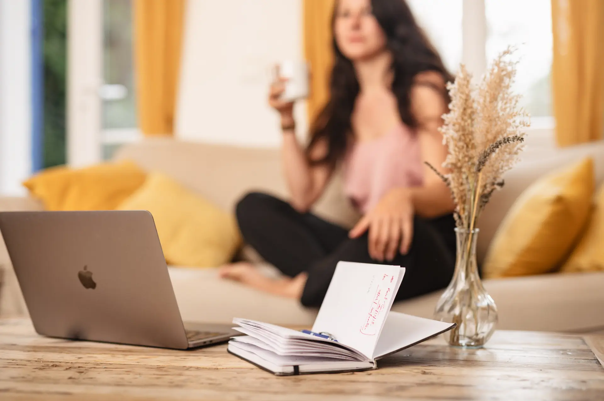 Élodie dans son salon, carnet et ordinateur sur la table